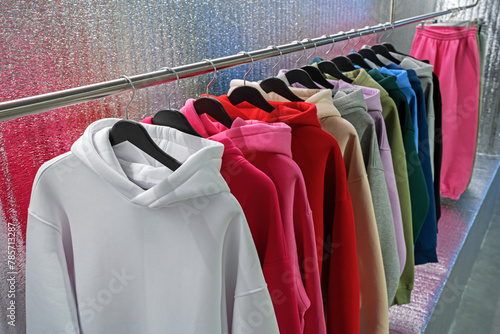 Hoodies on hangers in a clothing store. Row of colorful youth hooded sweatshirt on a clothes rack.