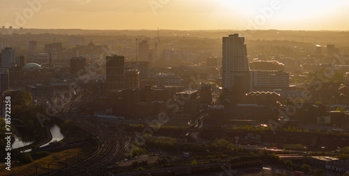 A serene cityscape of Leeds at sunrise, with the emerging daylight piercing through the morning haze revealing the city's West Yorkshire skyline and ongoing constructions © jmh-photography