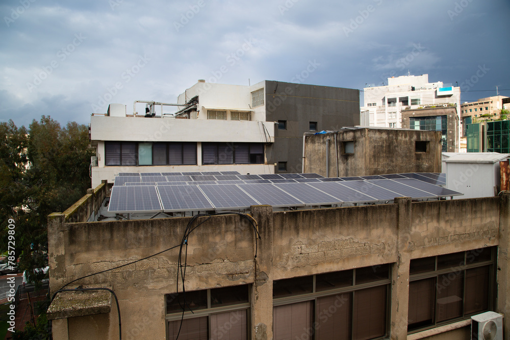 Solar panels atop urban buildings in Ramat Gan, Israel, under impending rainclouds