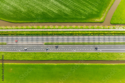 Drone view of a road in the middle of a field. Landscape from a drone. Road and transport. Car traffic. Rows on the field. View from above.