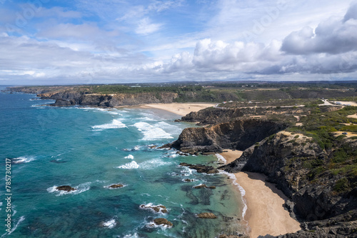 Drone view of Praia de Odeceixe beaches from the south - waves and underwater rocks and blue ocean water - cumulus clouds photo