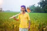 village farmer holding a gardening hoe on his shoulder in the crop field