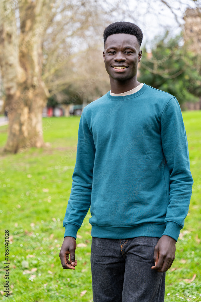 A young man wearing a blue sweater stands in a grassy field A young man wearing a blue sweater stands in a grassy field