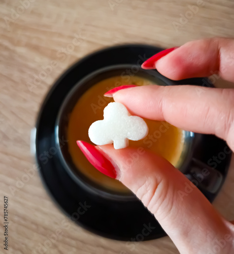 Clubs shaped sugar cube held over coffee cup espresso 
