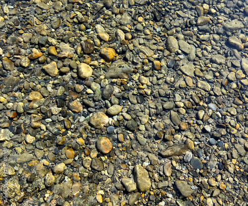 Filled background of river stones under clear water