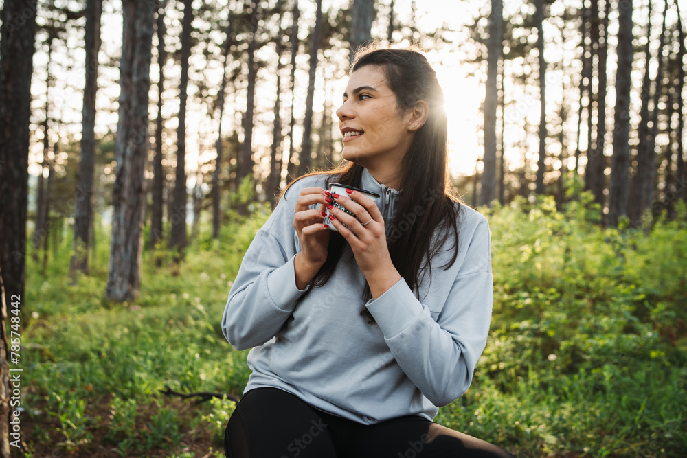 Young caucasian woman pouring and drinking water in forest while taking a break from hiking
Young caucasian woman pouring and drinking water in forest while taking a break from hiking