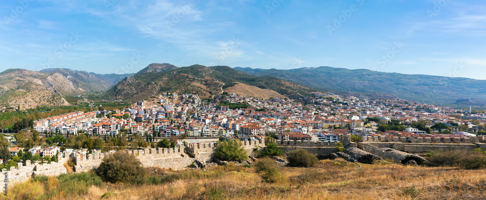 Naklejka premium Detailed panoramic view of Selcuk town with ancient walls, lush hills, clear skies, travel and culture themes. Banner. Selcuk, Izmir, Turkiye (Turkey)