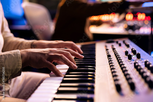 Male artist playing notes on electronic midi controller in studio, composing a new song with piano keyboard synthesizer. Skilled musician making a live performance in control room, music production.
