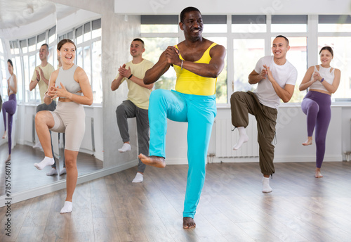 During dance workshop, African man with team of like-minded multinational people learn to perform elements of energy contemporary dance. Studio school for amateur and professional dancers