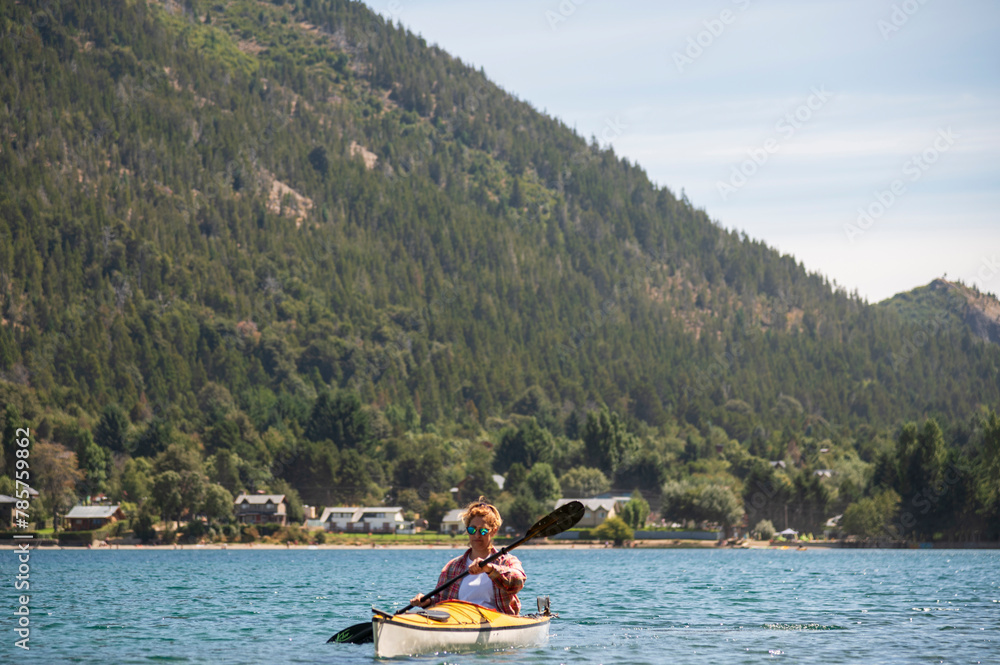 Beautiful Woman happily enjoys kayaking while paddling through the lakes of southern Argentina in Bariloche.