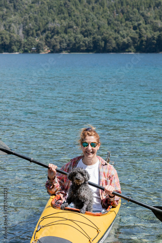 Beautiful young woman enjoys her best companion and friend her pet dog, while kayaking on the lakes of southern Argentina, Bariloche, Patagonia.