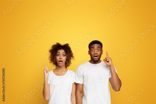 Stunned black man and woman pointing upward with opened mouths photo