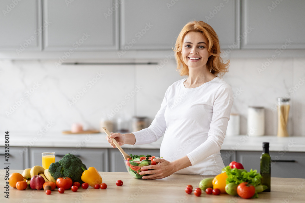 Pregnant woman preparing healthy salad in kitchen