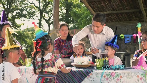 Latin family of the Mayan ethnic group, celebrates the birthday of their best son and everyone, together with a colorful cake, waits for the candles to be blown out. photo