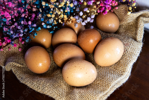 Farm chicken eggs lying on burlap against a background of flowers