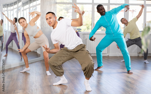 Positive Asian guy engaged in breakdancing together with other attendees of dancing courses