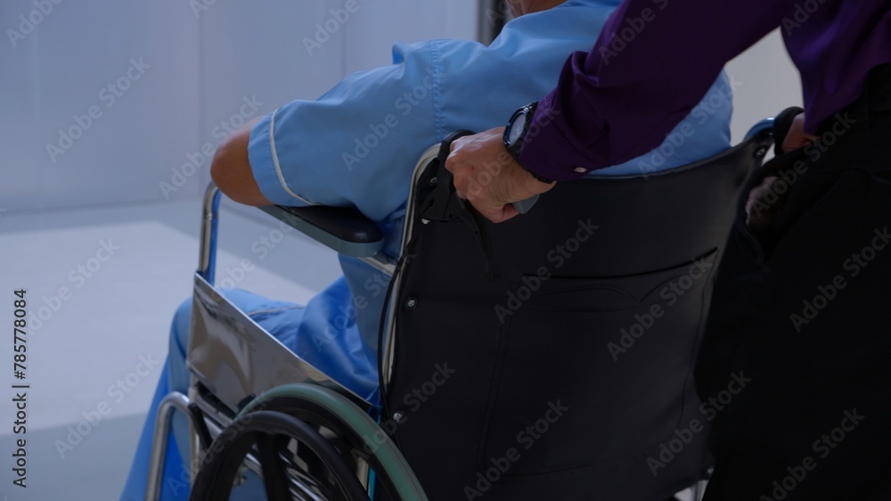 Young asian man pushing button with elevator while elderly father sitting on wheelchair at hospital, senior dad sitting on wheelchair and son pushing wheelchair to elevator, medical and insurance. Young asian man pushing button with elevator while elderly father sitting on wheelchair at hospital, senior dad sitting on wheelchair and son pushing wheelchair to elevator, medical and insurance.