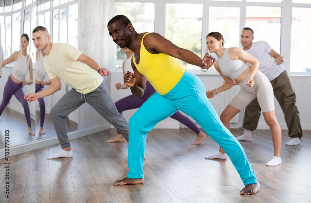Obraz premium Happy African american man and group of international dancers training before big performance in modern dance class