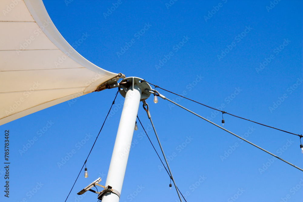 Fototapeta premium White tarpaulin canopy, stretched with steel wires, in the blue sky