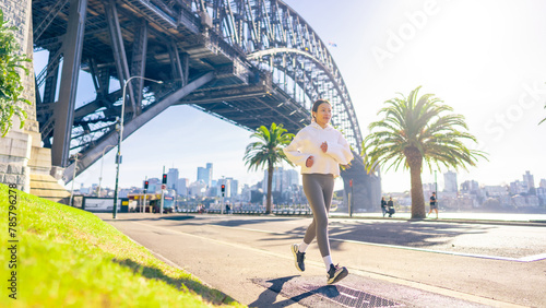 Photography Asian woman in sportswear listening to music with earphones and mobile phone app jogging workout exercise at city street in the morning