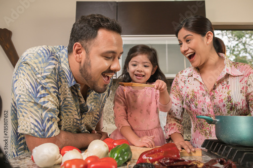 Daughter giving her father, in a wooden spoon, a sample of sauce that she has cooked with her mother. photo