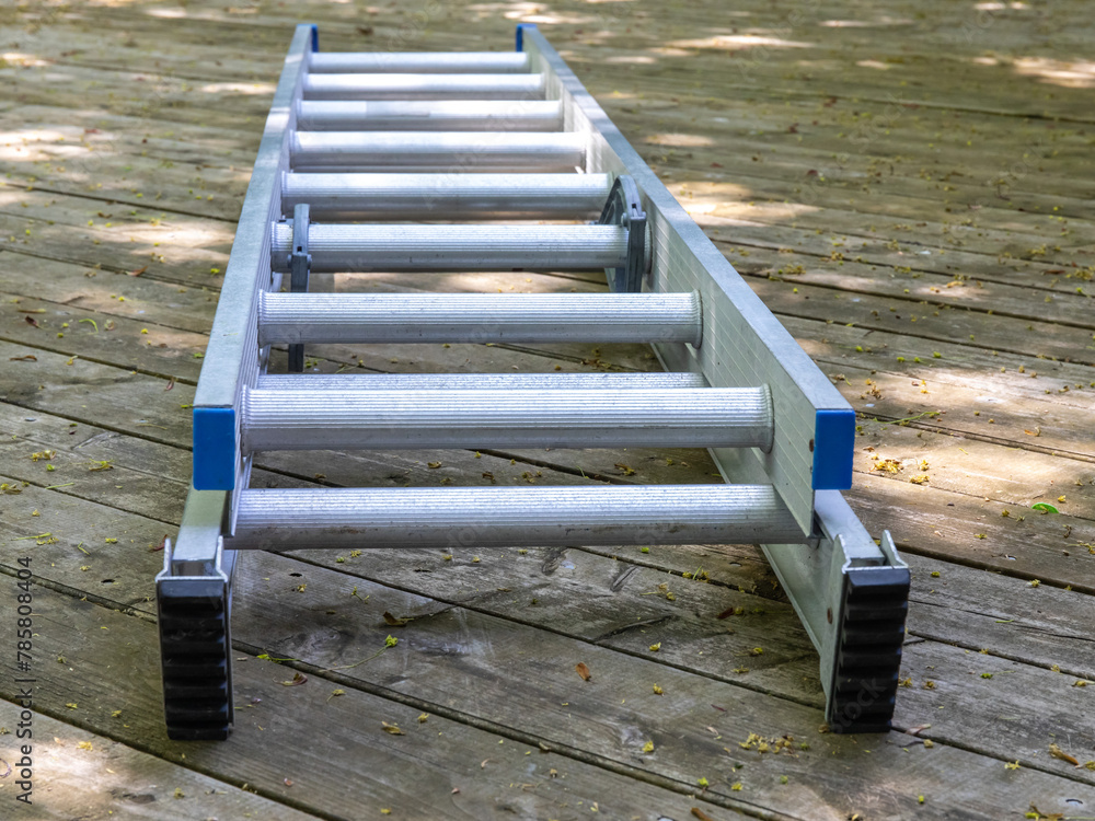 Fototapeta premium an aluminum extension ladder lying on a wooden deck