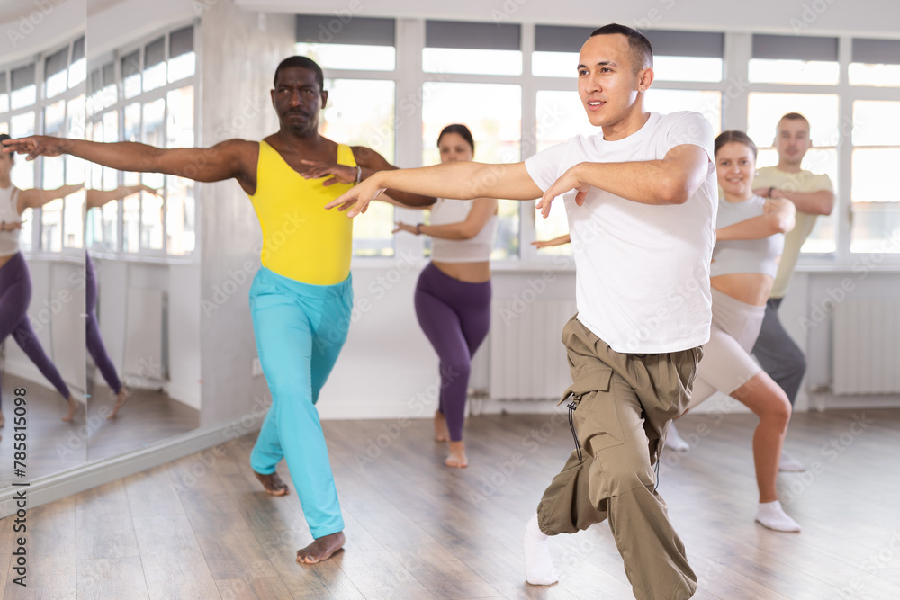 Fototapeta premium Group of multiethnic men and women rehearsing jazz funk dance in studio