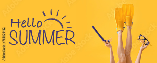Young woman with flippers, snorkeling mask and tube on yellow background. Hello Summer