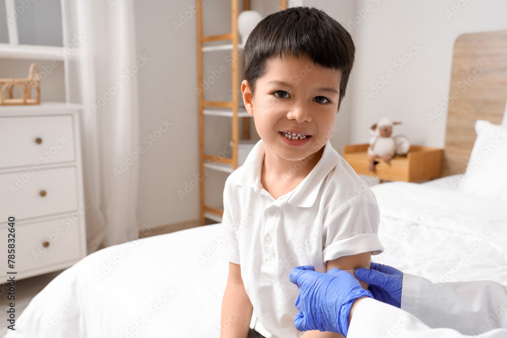 Little Asian boy receiving plaster from doctor after vaccination in bedroom Little Asian boy receiving plaster from doctor after vaccination in bedroom