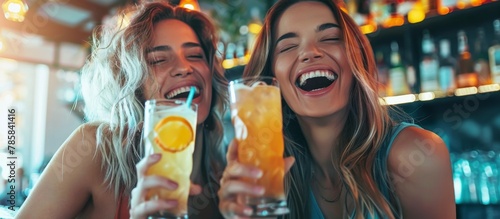 Two young females are joyfully laughing and enjoying a glass of fresh orange juice in a vibrant bar atmosphere
