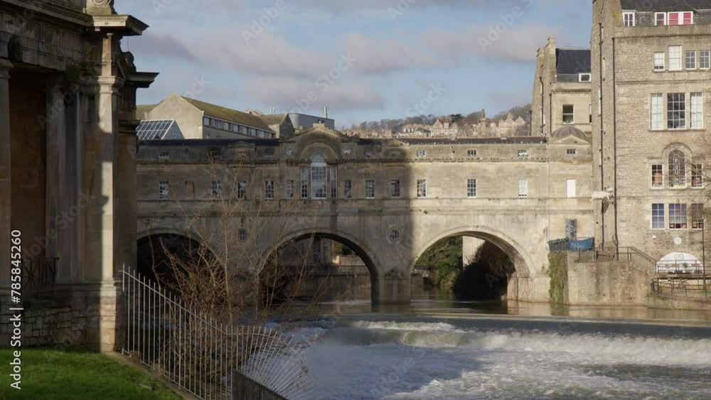 Water From River Avon Flowing Through The Weir Near The Pulteney Bridge In Bath, England. - wide shot Water From River Avon Flowing Through The Weir Near The Pulteney Bridge In Bath, England. - wide shot