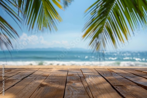 View of a tropical beach from a wooden deck with palm leaves in the foreground