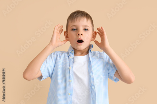 Shocked little boy on beige...