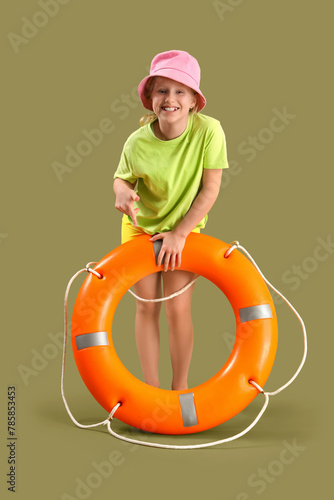 Happy little girl lifeguard pointing at ring buoy on green background