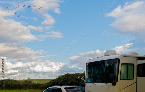 Ducks fly over Rv motorhome and vehicle on cloudy day