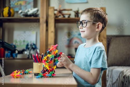 A child boy in the children's room is playing with a toy constructor for teaching the science of chemistry. Assembling molecules from elements. Children's scientific education