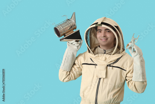 Male beekeeper with supplies on blue background photo