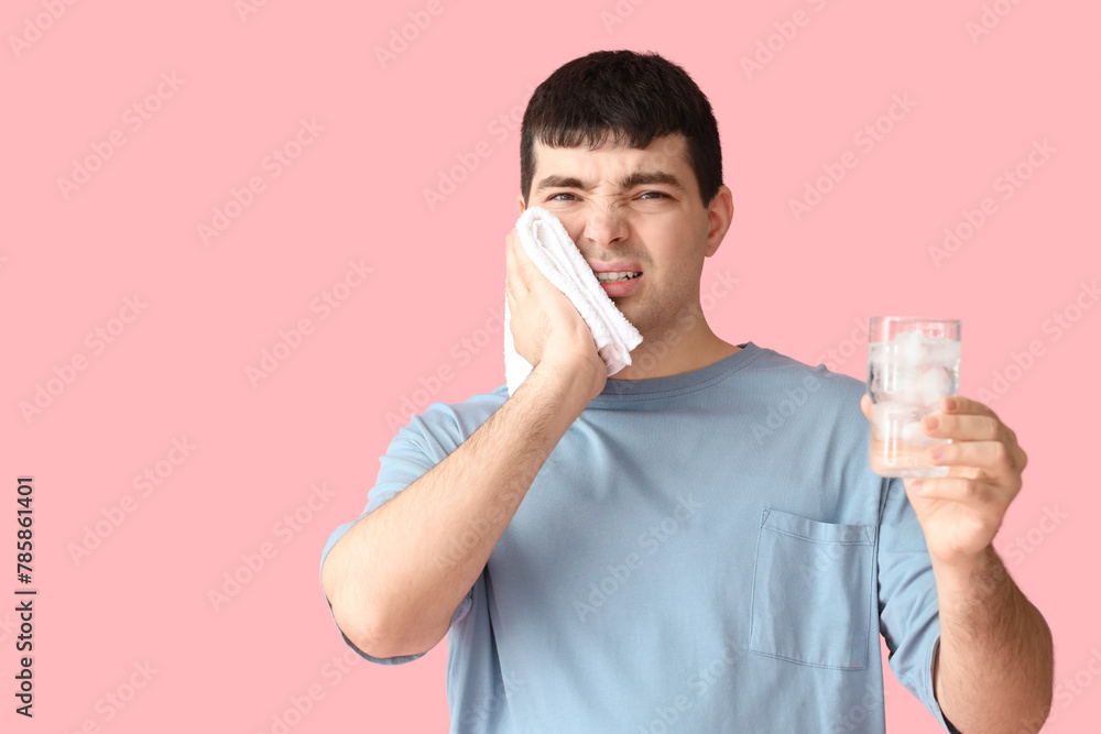 Young man with towel and cool water suffering from toothache on pink background, closeup Young man with towel and cool water suffering from toothache on pink background, closeup