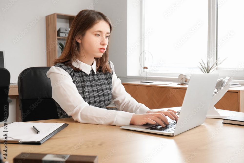 Pretty businesswoman working with modern laptop at table in office Pretty businesswoman working with modern laptop at table in office