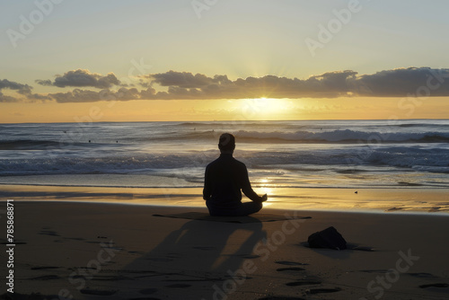 A person meditating on the beach at sunrise, their posture serene.
