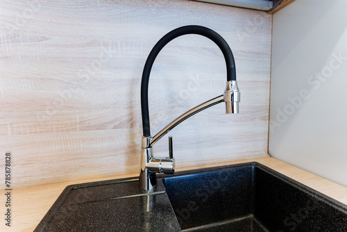 Black tap and hose on a wood sink, rectangularshaped, on hardwood flooring photo