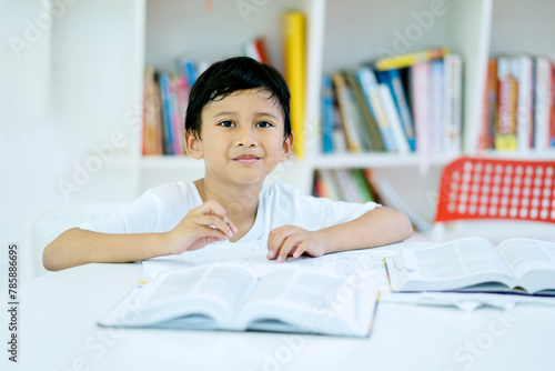 Asian boy reading a book in the library with bookshelf background