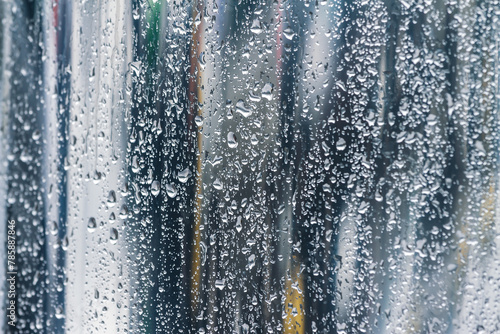 raindrops on glass window in rainy day with blurred street background.