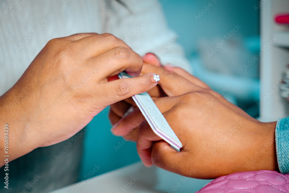 close-up of a latina manicurist filing a latina woman's nails - beauty concept close-up of a latina manicurist filing a latina woman's nails - beauty concept