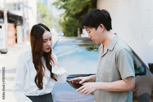 Young Asian female driver talking with car accident claim representative on the road, feeling stressed and concerned