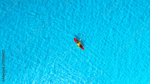 Aerial view of a woman and a young man kayaking on clear blue waters at Andaman Island. She does water sports activities.