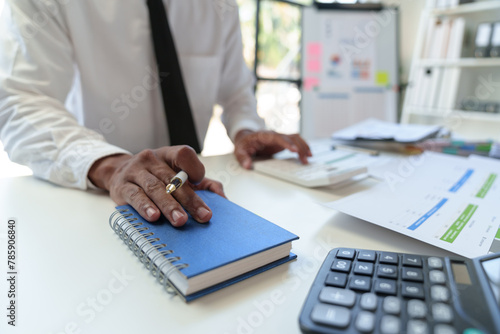 An Asian male finance worker or accountant is reviewing the investment results. To report at the meeting, audit ideas and investment results.