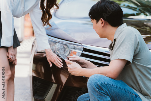 Car accident claim representative examining the accident with young Asian female driver talking with on the road