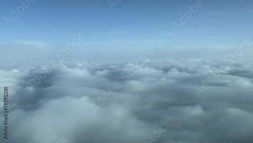 Exclusive aerial shot from a plane cockpit while flying over a blanket os stratus clouds. Immersive pilot POV. Daylight, blue sky. 4K 60FPS photo