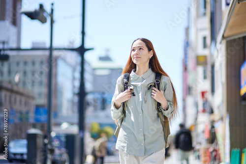 バックパックを背負って都会を歩く女性の外国人旅行者